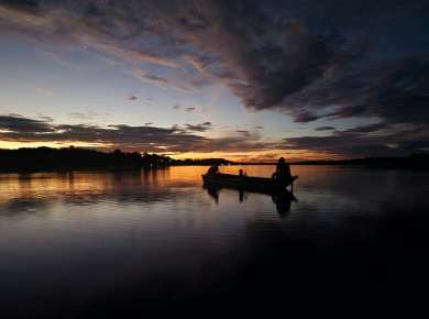 a boat floating on top of a lake under a cloudy sky