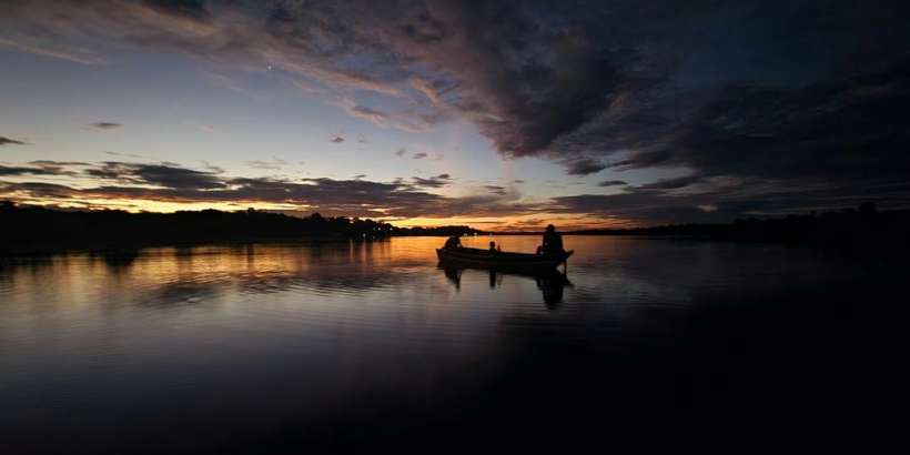 a boat floating on top of a lake under a cloudy sky