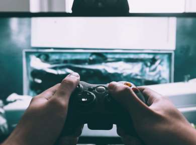 person holding game controller in-front of television
